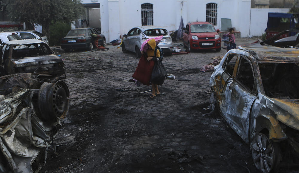A Palestinian carries belongings in the parking lot of the al-Ahli Arab Hospital in Gaza City on Oct. 18. Palestinian officials blamed an explosion a day earlier on an Israeli airstrike. But Israel said the cause was an errant Palestinian rocket. The U.S. and other Western intelligence agencies also said the evidence pointed to a Palestinian rocket.