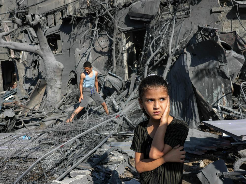 A girl looks on as she stands by the rubble outside a building hit by Israeli bombardment in the southern Gaza Strip on October 31, 2023. Children in Gaza have been exposed to high levels of violence even before the current war, researchers say, increasing their risk of mental health challenges.