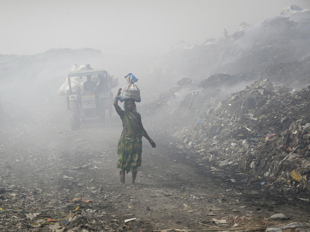 People work at a landfill in India that's full of plastic bags. Members of the United Nations are negotiating a treaty that's aimed at cutting plastic pollution globally.
