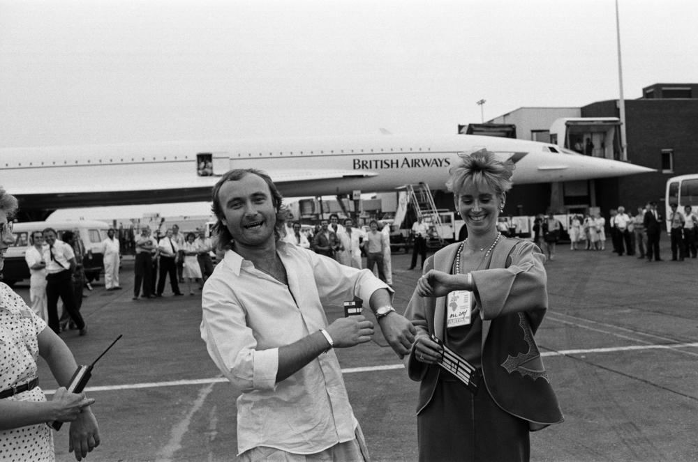 Singer Phil Collins and his wife Jill Tavelman check their watches at London's Heathrow Airport on July 13, 1985. Collins boarded a Concorde and flew to the U.S. for a Live Aid benefit concert in Philadelphia — after playing the London stage the same day.