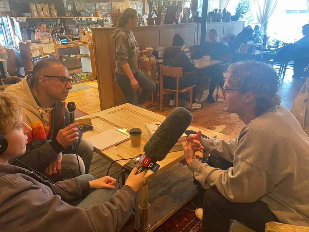 <em>Morning Edition</em> host A Martinez (L) speaks with Dordt University junior Carter King (R) about next year's presidential election. The <em>Morning Edition</em> team met with King, who is originally form Austin, Texas, at The Fruited Plain Café in Sioux Center, Iowa.