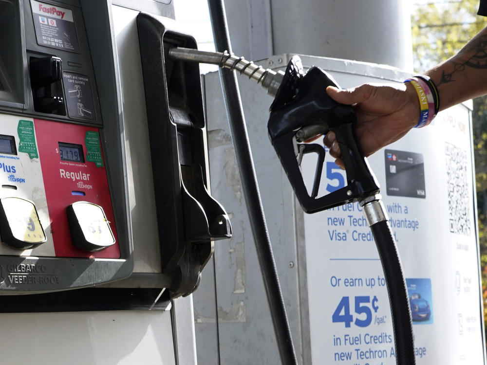 A customer replaces the pump dispenser at a Chevron gas station in Columbus, Miss., on Oct. 23. The average price of regular gas has fallen more than 40 cents from a year ago.