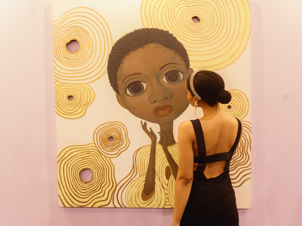 An attendee views one of rising artist Adulphina Imuede's dreamlike illustrations at ART X.