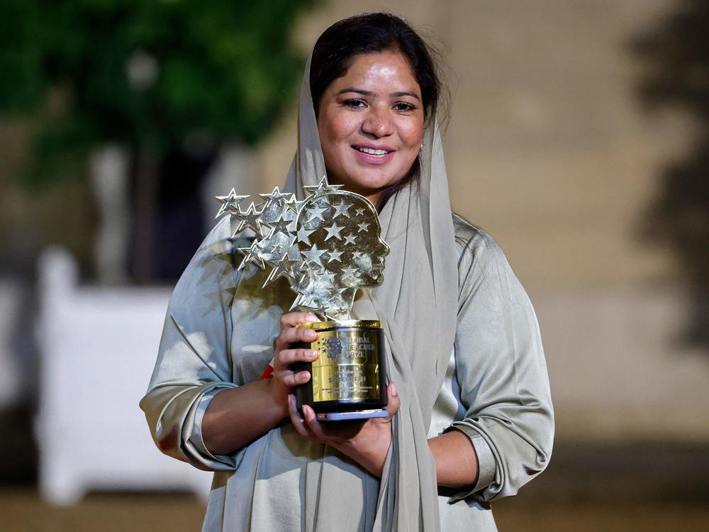 Pakistani teacher Riffat Arif, known as Sister Zeph, is the 2023 winner of the Varkey Foundation Global Teacher Prize. She holds a trophy presented at a dinner in her honor in Paris. She says she faced bad treatment from her teachers at school and dreamed of 