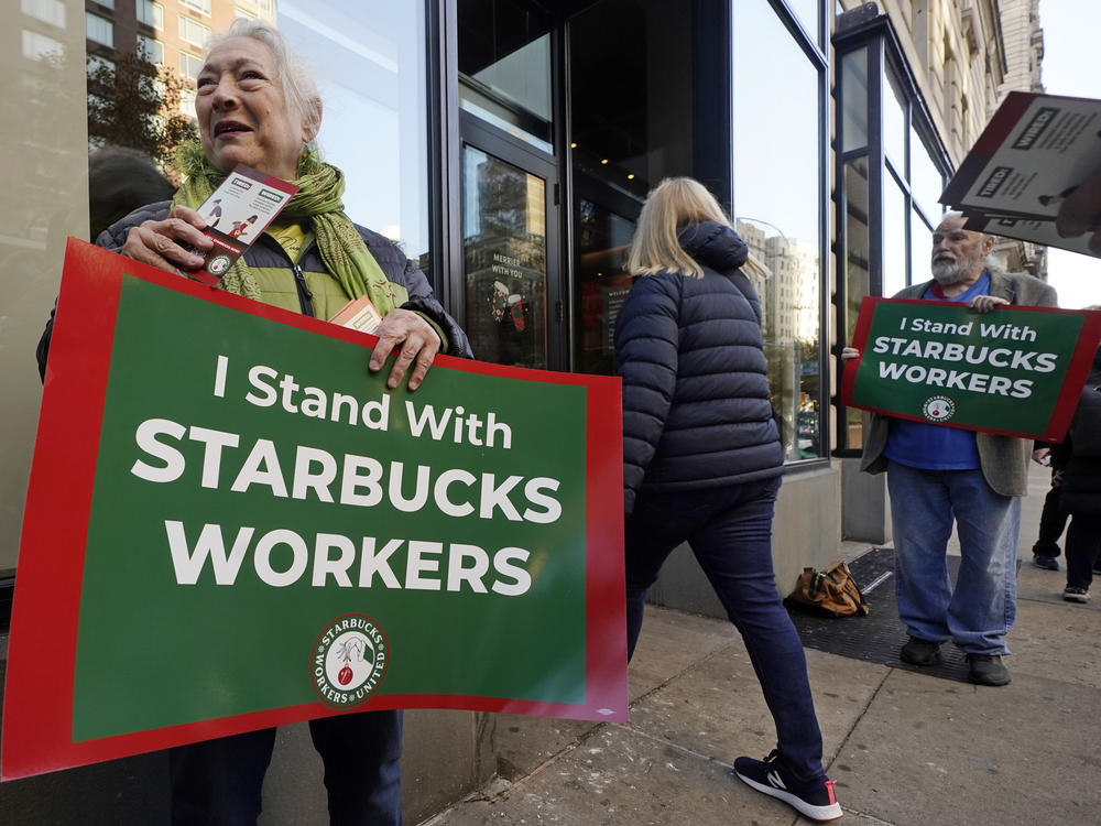 People hold signs supporting Starbucks workers outside a Starbucks on New York's Upper West Side on Thursday.