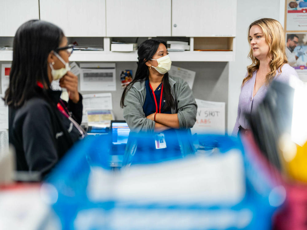 Ashley Close, staff attorney at Children's Law Center, right, checks in with Dr. Ankita Khandai, center, and Dr. Candice Dawes, left, at Children's National's Anacostia clinic in Washington, D.C. Close works with doctors to help them fight for healthy living conditions for patients. Medical-legal partnerships like this are spreading nationwide.