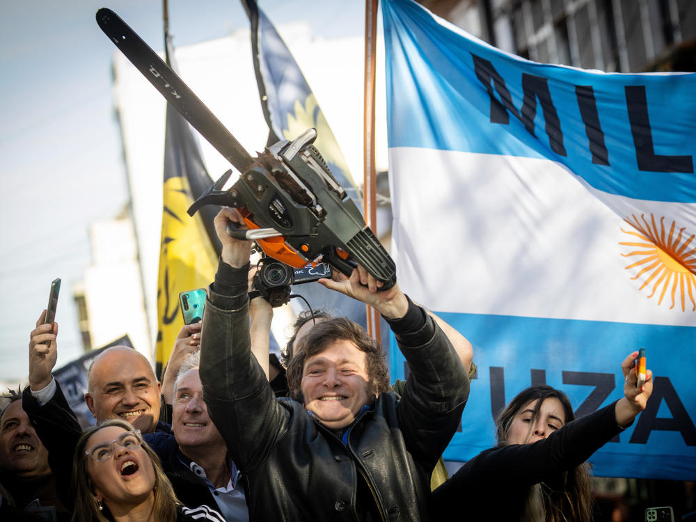 Javier Milei of La Libertad Avanza lifts a chainsaw next to the Buenos Aires province governor candidate Carolina Piparo of the same party during a campaign rally.