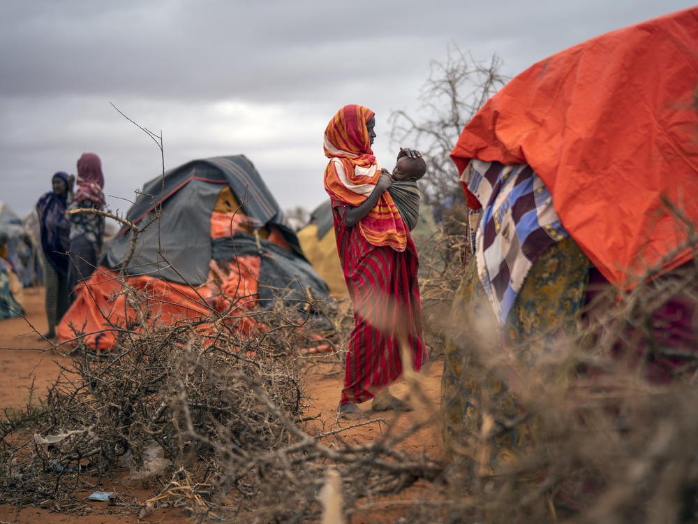 A woman breastfeeds her child at a camp for displaced people in Somalia, where climate change is fueling severe drought.