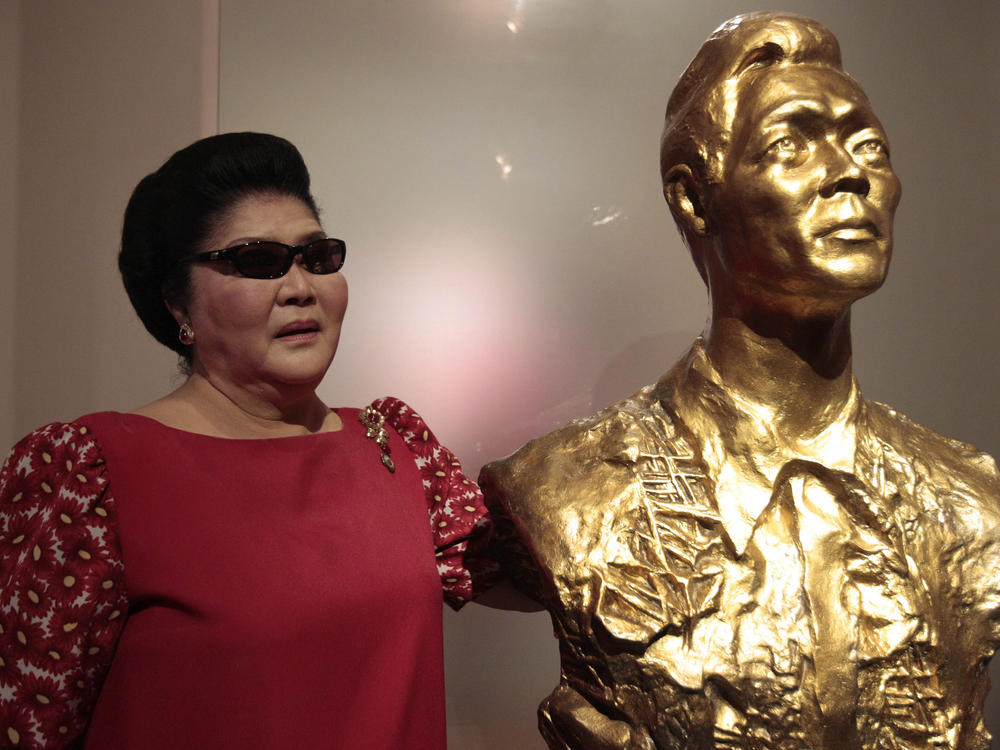 Former Philippine first lady Imelda Marcos stands beside a bust of her husband, Ferdinand, at Ilocos Norte province, northern Philippines, in 2013.