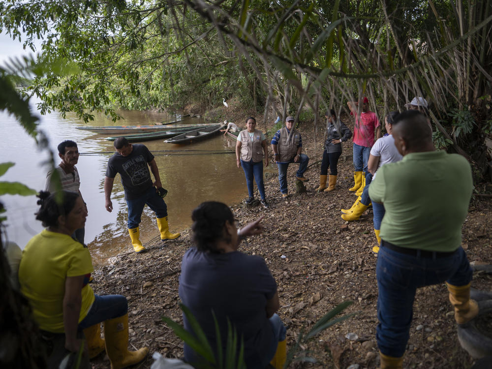 Yuly Velásquez (center in tan vest) president of a local fishers association and a clean-water advocate, meets with its members on a tributary of the Magdalena River. She has been attacked three times in the past two years for her environmental work.