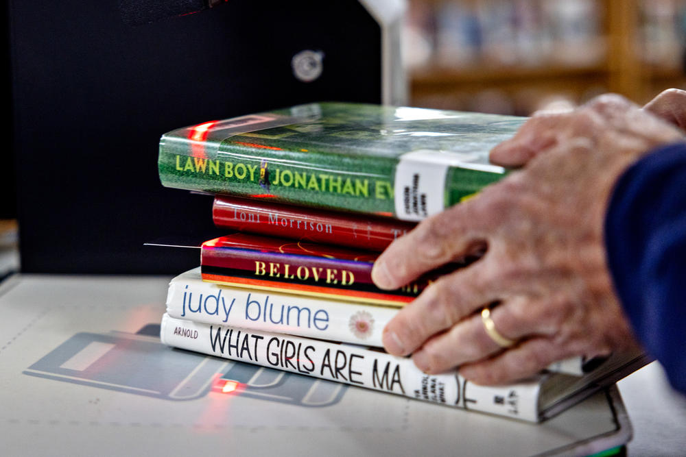 Parents Against Bad Books co-founder Tom Harrison grabs a stack of what group members call age-inappropriate books that they checked out from the Idaho Falls Public Library on Oct. 4.