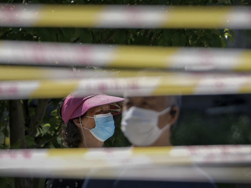 Residents wearing face masks line up behind barricaded tapes for COVID mass testing near a residential area on May 15, 2022, in Beijing. The World Health Organization says it's made an official request to China for information about a potentially worrying spike in respiratory illnesses and clusters of pneumonia in children.