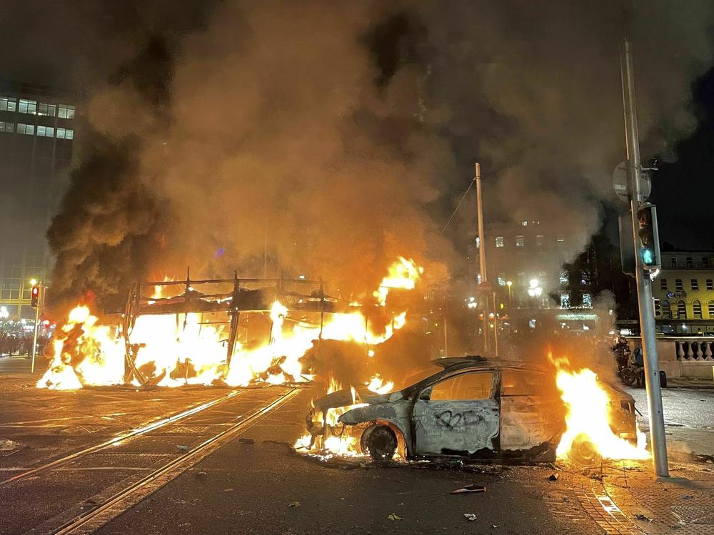 A bus and car on fire after violent scenes unfolded in Dublin city center, Thursday Nov. 23, 2023 following a knife attack.