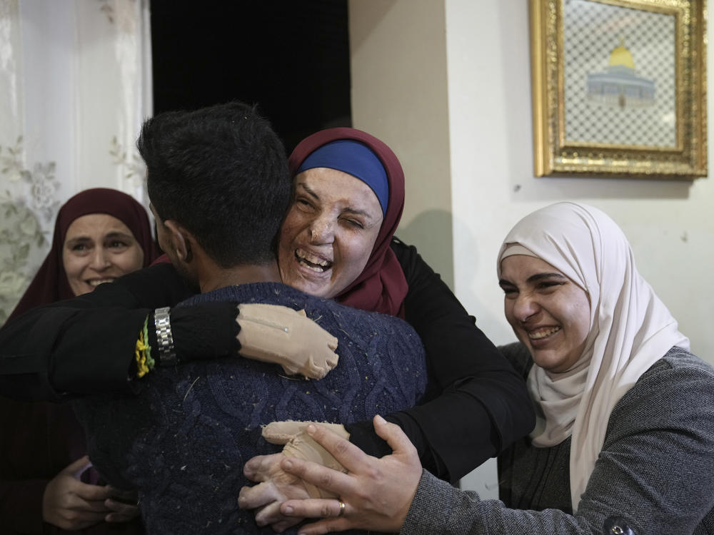 Israa Jaabis, center, a Palestinian prisoner released by Israel, is hugged by relatives as she arrives home in the east Jerusalem neighborhood of Jabel Mukaber, early Sunday Nov. 26, 2023.