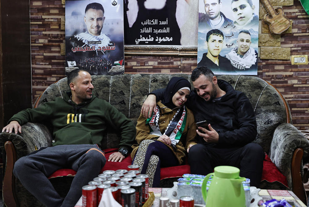 Asil al-Titi, a 23-year-old former prisoner from the occupied West Bank, sits between her two brothers on Nov. 25, 2023 at the famiy home in the Balata refugee camp, one day after her release from Israeli jail in exchange for hostages held in Gaza by Hamas.