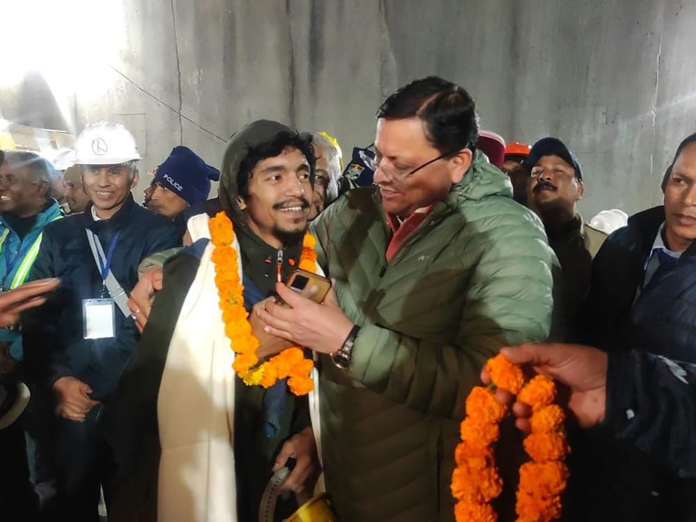 This handout photo provided by the Uttarakhand State Department of Information and Public Relations shows Pushkar Singh Dhami (right), chief minister of the state of Uttarakhand, greeting a worker rescued from the site of a collapsed tunnel in Silkyara in the northern Indian state of Uttarakhand.