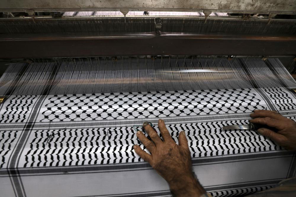A worker cuts excess strings at a textile factory producing the keffiyeh in the occupied West Bank city of Hebron on Nov. 20.
