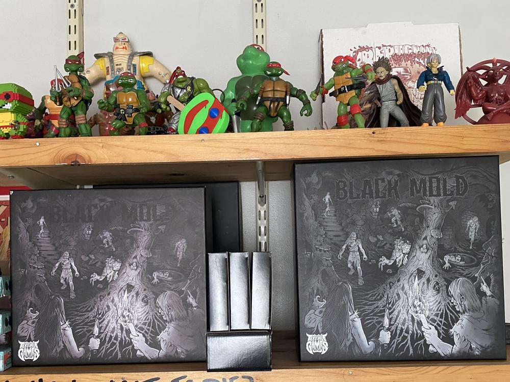 John de Campos says he spent 50 or 60 hours on illustrations for his latest board game Black Mold, which he describes as a survival horror escape. Some of his competitors in the board game space are turning to AI for art.