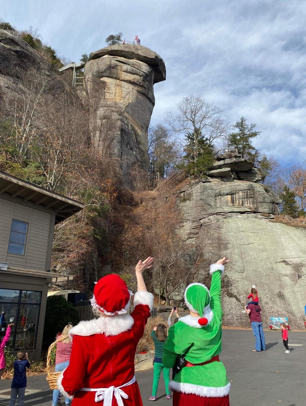 Spectators cheer as Santa rappels down Chimney Rock in 2022. The day is also filled with events like guided hikes and nature crafts.