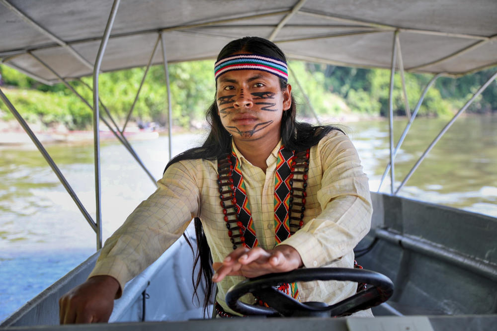Luciano Peas, a 27-year-old Indigenous boat driver from the village of Sharamentsa, steers one of the solar-powered canoes. The project is run on the ground exclusively by Indigenous people.
