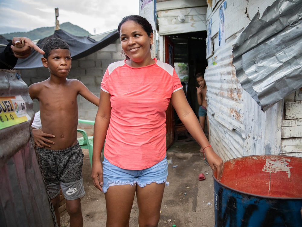 In La Paz, a low-income neighborhood on the outskirts of Santa Marta, Colombia, water service from the local utility can be erratic or nonexistent. Pictured: Neighborhood kids stand next to a rain barrel positioned under a corrugated roof.