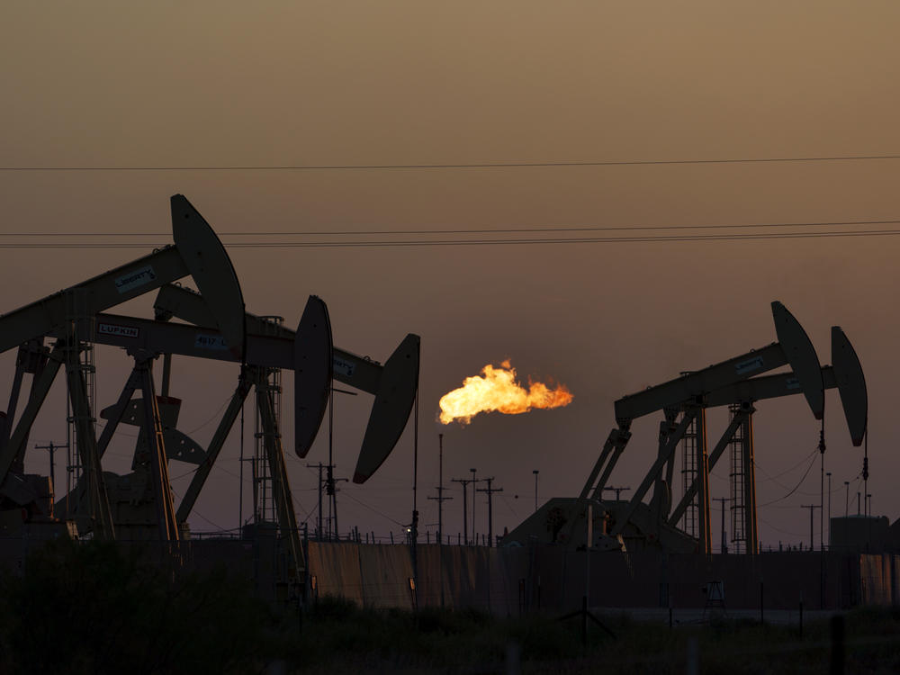 A flare burns off methane and other hydrocarbons as oil pumpjacks operate in the Permian Basin in Midland, Texas, Oct. 12, 2021.