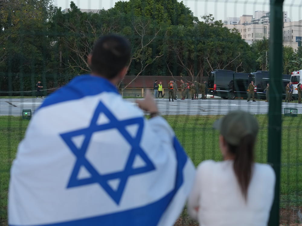 A man wearing an Israeli flag looks toward ambulances outside a hospital in Petah Tikva, Israel, on Nov. 24.