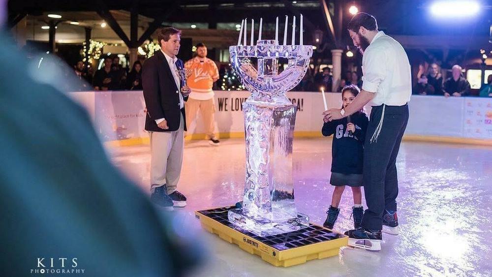 Rabbi Shaul Perlstein gets help lighting the ice menorah in 2018.