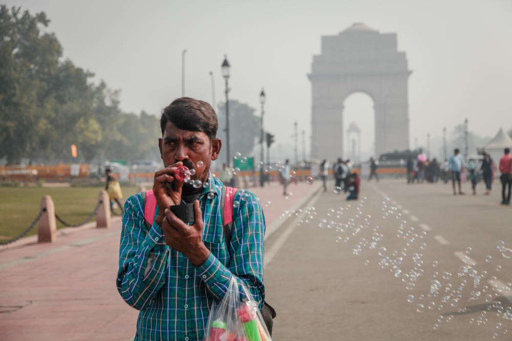 Gajender Kohli blows bubbles to attract customers near India Gate in New Delhi. He says the air pollution hurts business. 
