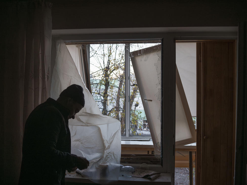A man uses plastic to cover a broken window in his apartment following a Russian drone attack in Kyiv, Ukraine, on Nov. 25.