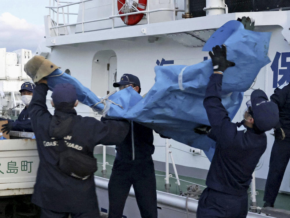 Members of the Japanese Coast Guard carry debris believed to be from the crashed U.S. military Osprey aircraft at a port in Yakushima, southern Japan, on Monday.