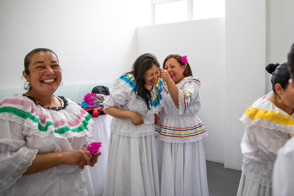 Ruth Infante, segunda desde la izquierda, madre soltera de tres hijos, y sus compañeras de clase, lucen vestidos tradicionales vaporosos para una presentación de danzas de cumbia en un centro de cuidados en Bogotá, Colombia. Esta clase forma parte de los servicios gratuitos disponibles para cualquier persona del barrio que se dedique al cuidado no remunerado de su familia.