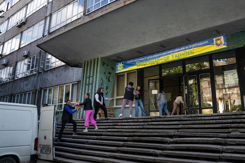 People at community center in Zaporizhzhia pack a truck with boxes of humanitarian aid to deliver to some of Enerhodar's displaced population in the area.