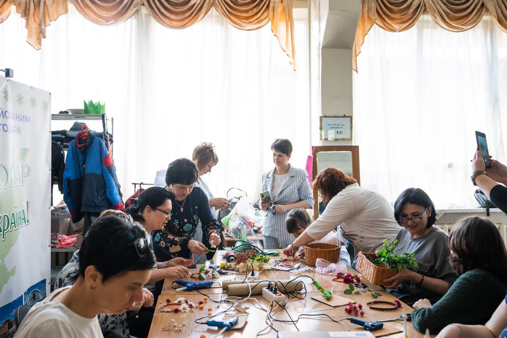 People from Enerhodar and former plant workers make flower crowns with children at a community center in Zaporizhzhia that serves some of Enerhodar's displaced population.