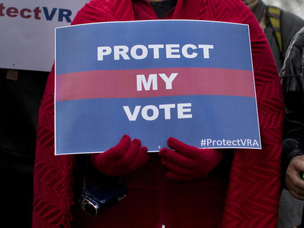 People carrying signs in support of the Voting Rights Act line up outside the U.S. Supreme Court in Washington, D.C., in 2013.