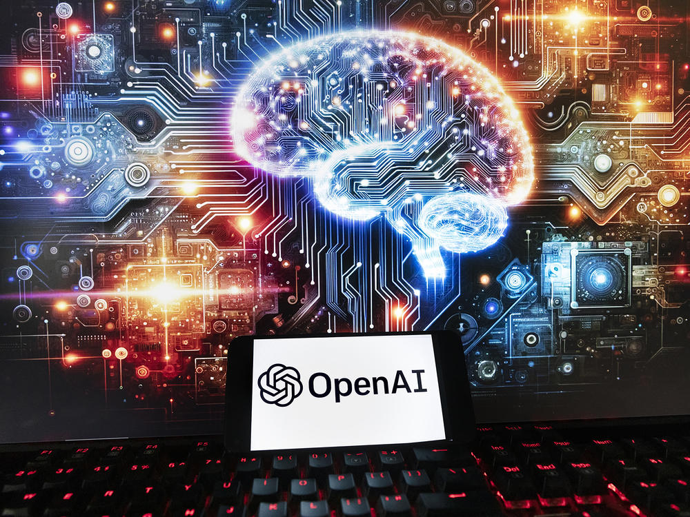 The OpenAI logo is displayed on a cellphone with an image on a computer monitor generated by ChatGPT's Dall-E text-to-image model in Boston on Dec. 8, 2023.