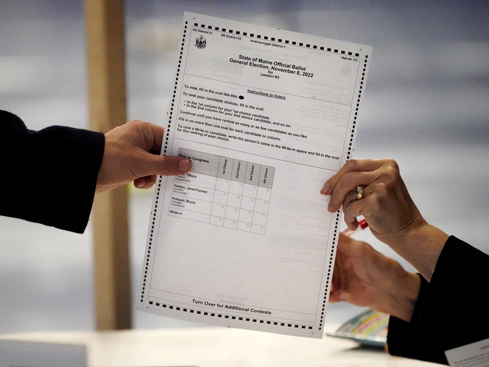 A clerk hands a ballot to a voter on Election Day, Nov. 8, 2022, in Lewiston, Maine. The state is one of 50 American voting jurisdictions to have moved to a ranked choice voting system, and more places may follow next year.