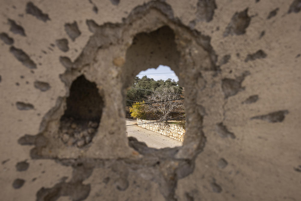 An olive tree is seen through a hole created by an Israeli attack in Kfar Kela, southern Lebanon.