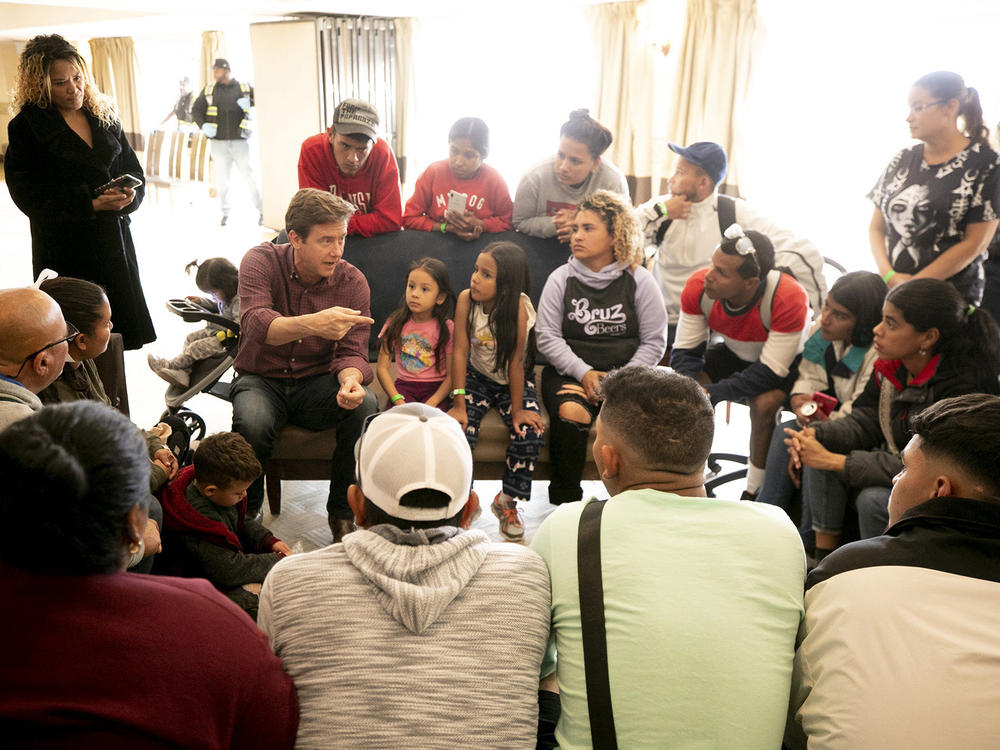 Denver Mayor Mike Johnston speaks with a group of migrants, many of whom are living outside, in a hotel run by the city. Nov. 18, 2023.