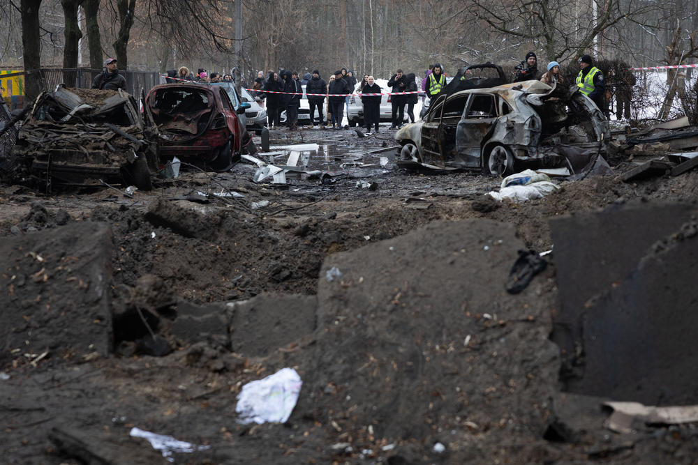 Residents stand near their apartment building, damaged during a Russian missile strike in Ukraine's capital Kyiv. Dozens were injured during the early hours of Dec. 13 after air defense systems intercepted incoming Russian ballistic targets.