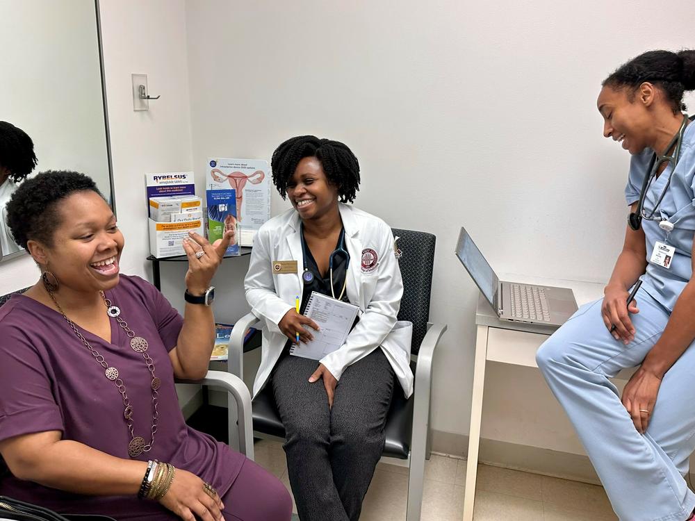 YaSheka Shaw (left) celebrates losing weight during a checkup with medical student Kaniya Pierre Louis (center) and Dr. Zita Magloire.
