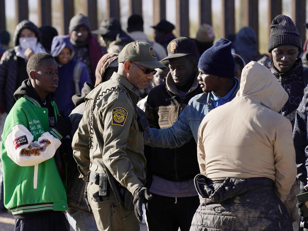 A group of migrants gather along the border after breaking through gaps in the border wall Tuesday, Dec. 5, 2023, in Lukeville, Ariz.