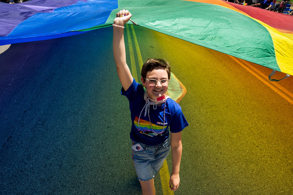 Sophia Lewis, 13, of Maryland Heights, Mo., helps hoist a giant rainbow flag down Market Street on June 25, 2023, during the St. Louis PrideFest Parade in downtown St. Louis.