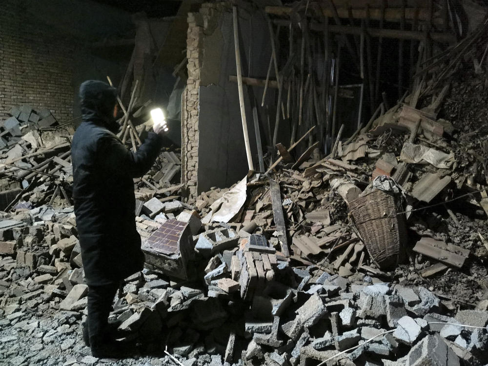 A government worker looks at the debris of a house brought down in the earthquake in Jishishan county in northwest China's Gansu province Tuesday, Dec. 19, 2023.