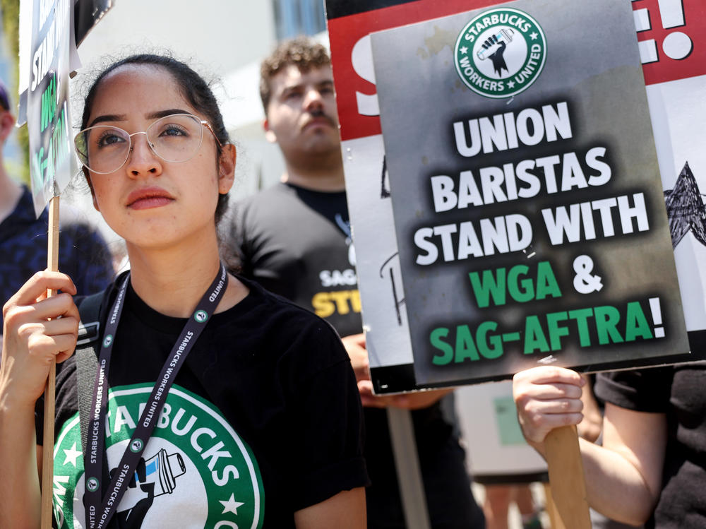 Starbucks workers including barista Kat Ramos stand with striking SAG-AFTRA and Writers Guild of America members on the picket line in solidarity outside Netflix studios on July 28, 2023 in Los Angeles, Calif.