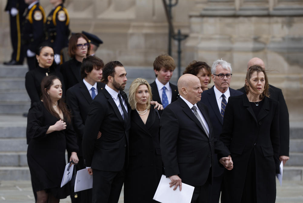 Family members of the late retired Supreme Court Justice Sandra Day O'Connor look on as O'Connor's casket is placed in a hearse after her funeral service.