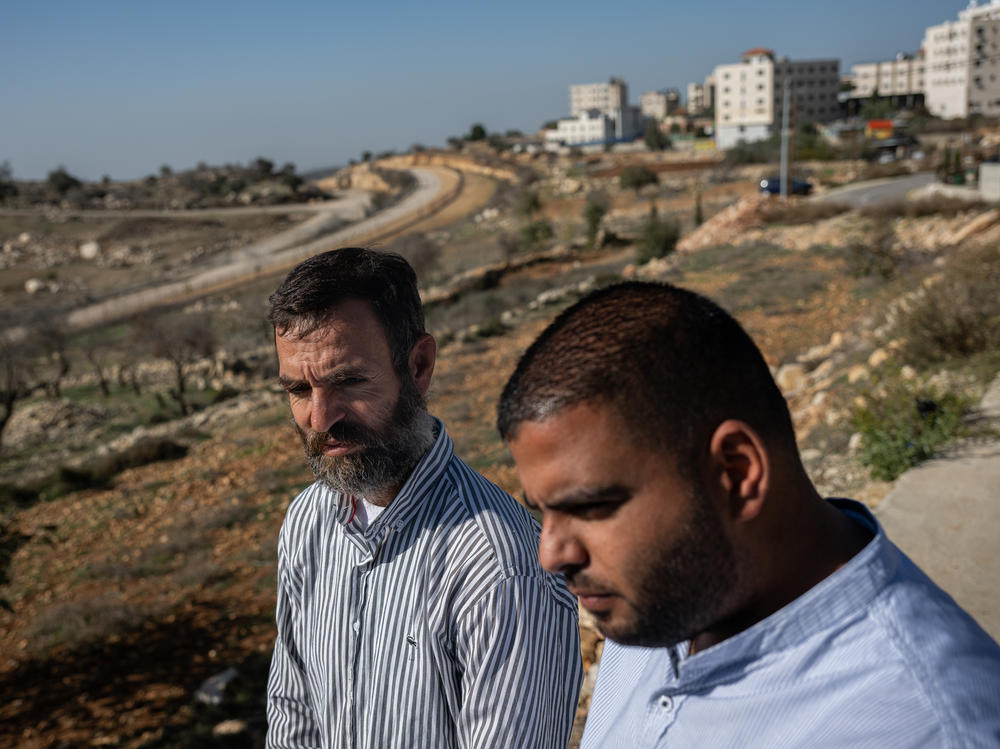 Palestinian farmers Naser El Khatib and Thaer El Taher stand on land filled with their olive trees at the edge of Beitunia, across from an area controlled by Israel in the occupied West Bank, on Dec. 2.
