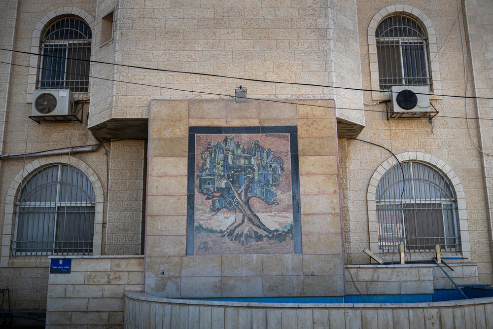 A mosaic depicting a community within an olive tree is built into the wall of the municipality building in Beitunia.