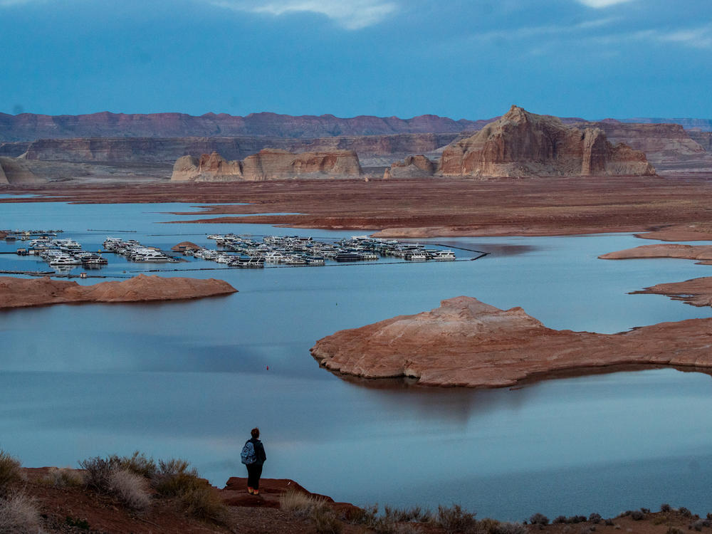 The Wahweap Marina, squeezed by the dropping and encroaching shoreline of Lake Powell on the Colorado River behind the Glen Canyon Dam outside Page, Ariz., on Feb. 20, 2023. The bathtub ring marking the once-high level of the lake is visible on the red rock formations in the distance. Full story <a href=