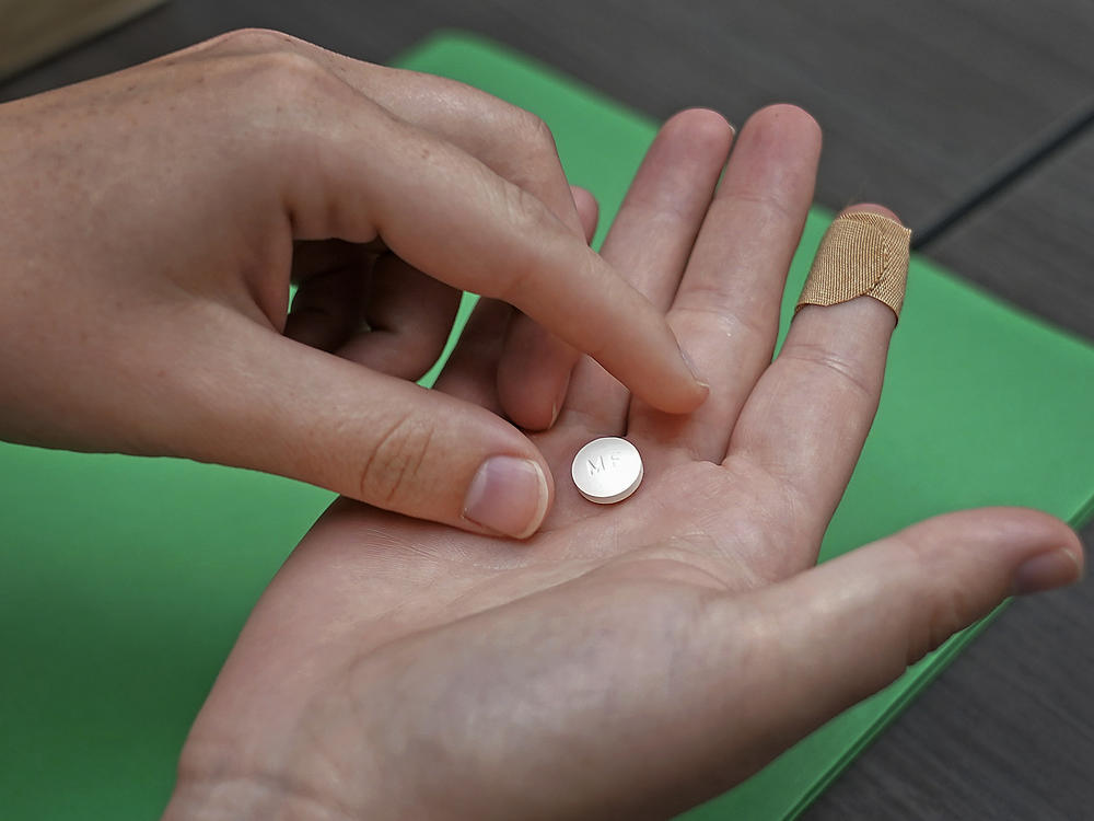 A patient prepares to take the first of two combination pills, mifepristone, for a medication abortion during a visit to a clinic in Kansas City, Kan., on Oct. 12, 2022.